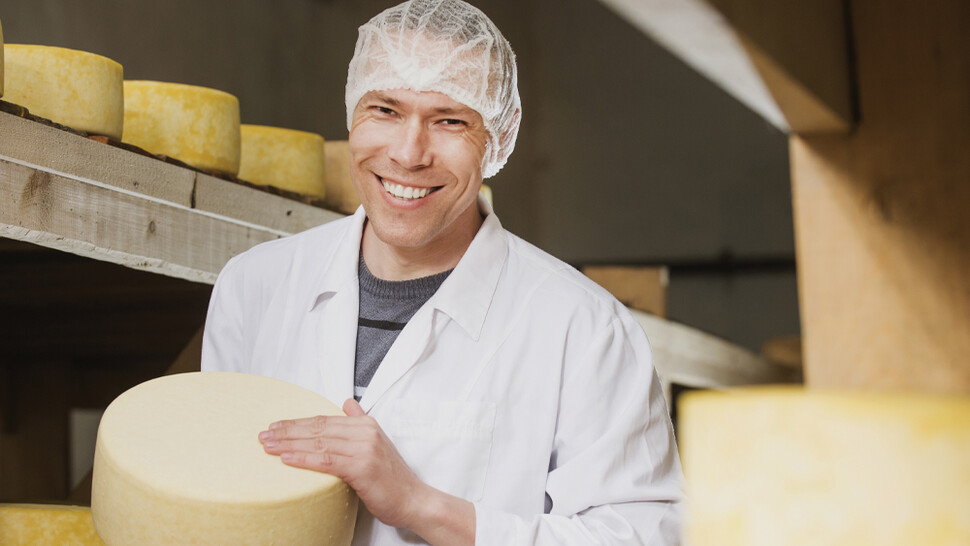 Employee holding wheel of cheese